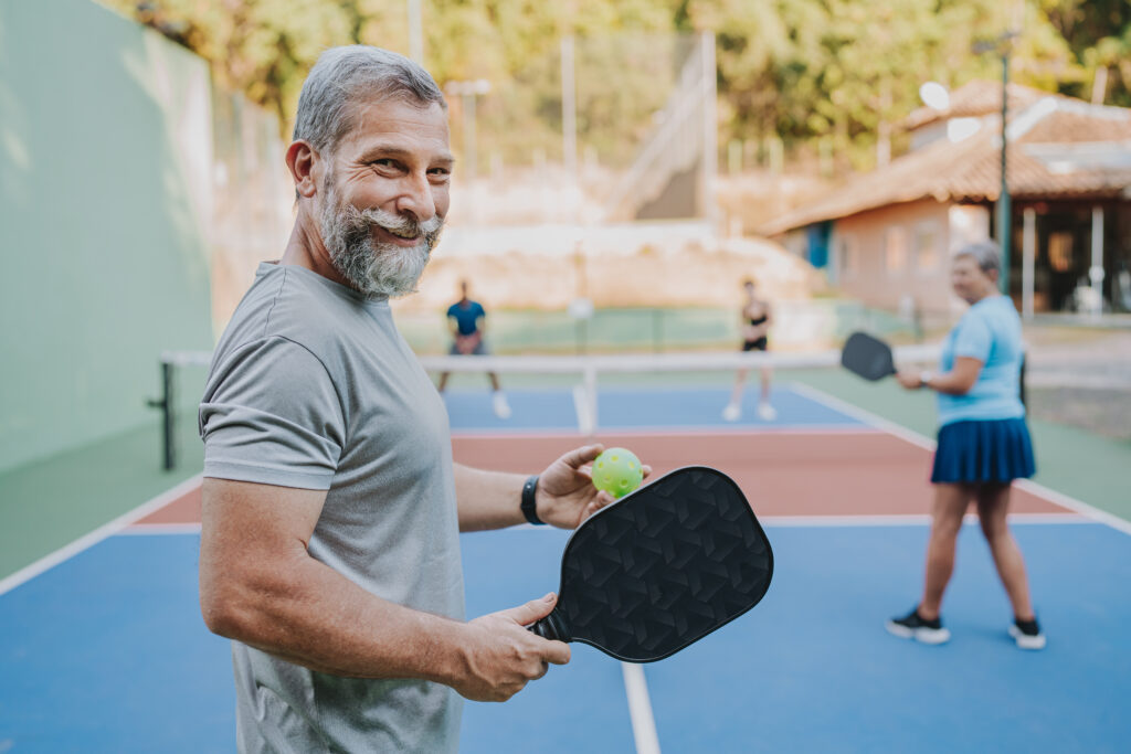 Portrait elderly man looking at camera pickleball game
